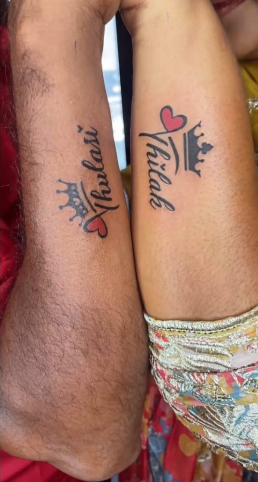 Matching couple name tattoos with crown and heart lettering on forearms