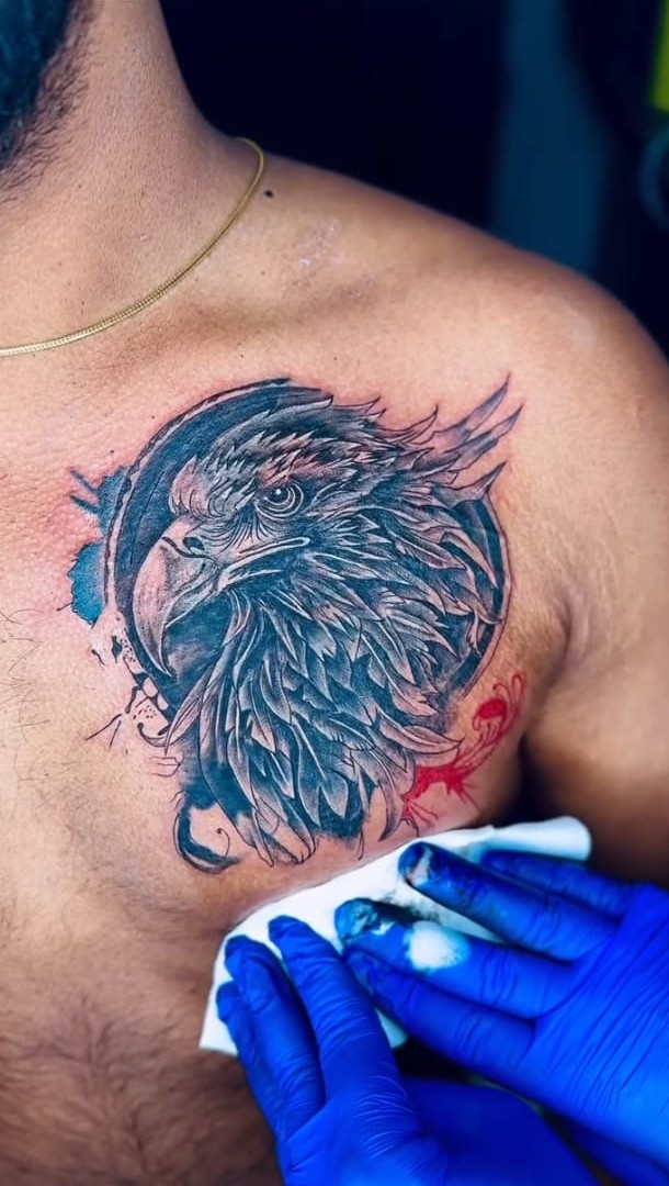 Detailed eagle head tattoo on the chest with fine feather linework